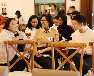 demo day 2025 Tim sedang diskusi santai di meja, suasana meeting informal dengan kursi kayu